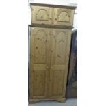 A modern Ducal honey coloured pine wardrobe, enclosed by a pair of twin panelled, full-height doors,