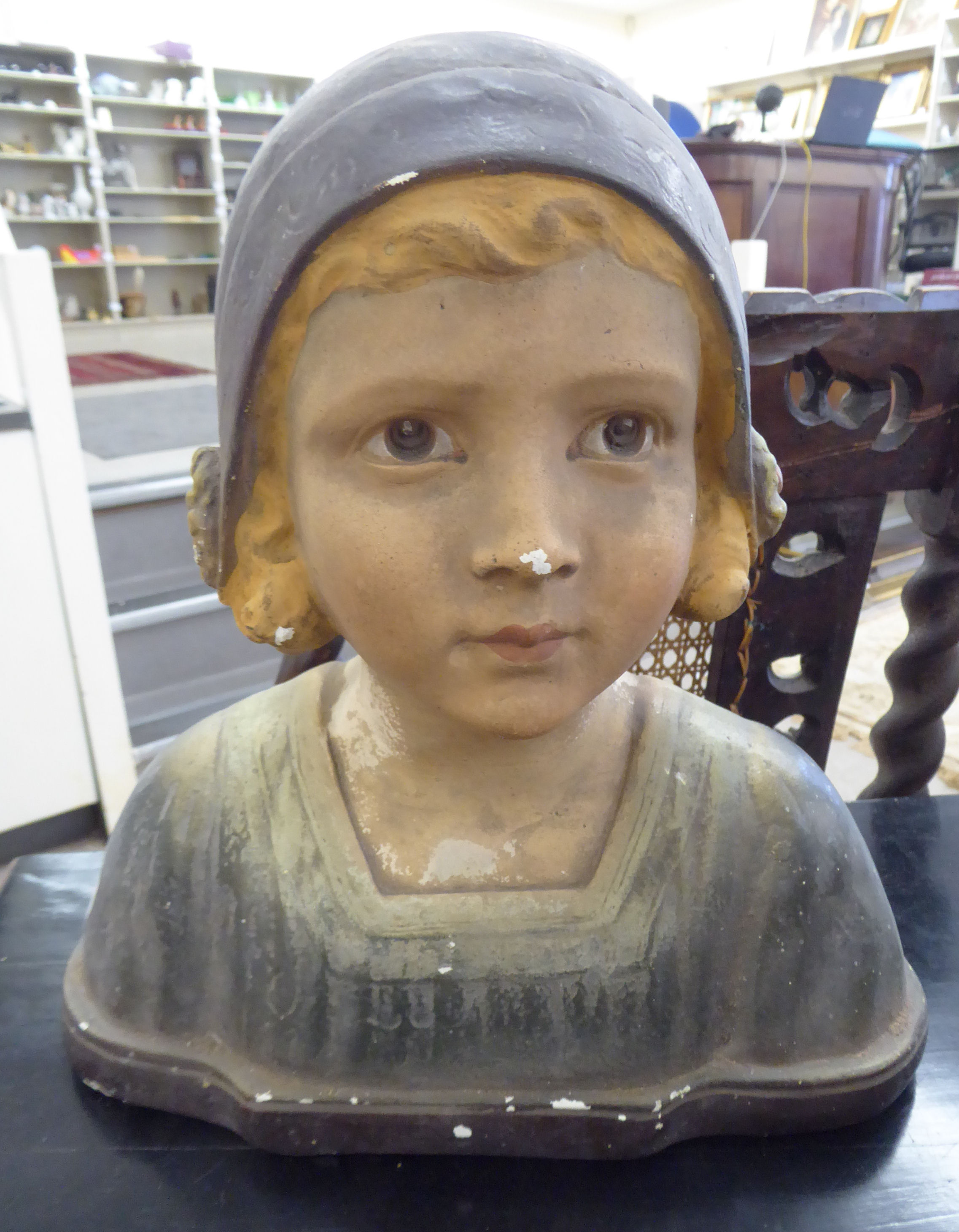 A 1920s painted plaster bust, a girl wearing a cap bears various indistinct impressions 13.