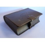 A brass and lead lined trinket box, fashioned as a book with a folding clasp on the hinged lid,