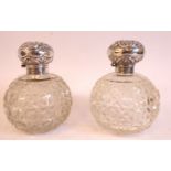 A pair of Edwardian spherical slice and hobnail cut glass perfume bottles with applied silver