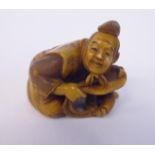 A late 19thC stained and carved ivory netsuke, depicting a kneeling man,