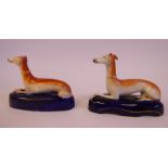 Two similar 19thC Staffordshire pottery model seated greyhounds with crossed front paws,