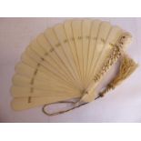 An early 20thC carved ivory fan with plain, tapered sticks,