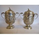 A pair of 19thC Continental silver coloured metal twin C-scrolled handled pedestal cups and covers,