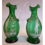 In the manner of Mary Gregory - a pair of green glass ovoid shaped ewers, having drawn,