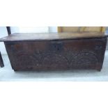 A late 17th/early 18thC boarded oak chest with a hinged lid, over a lunette carved, panelled front,