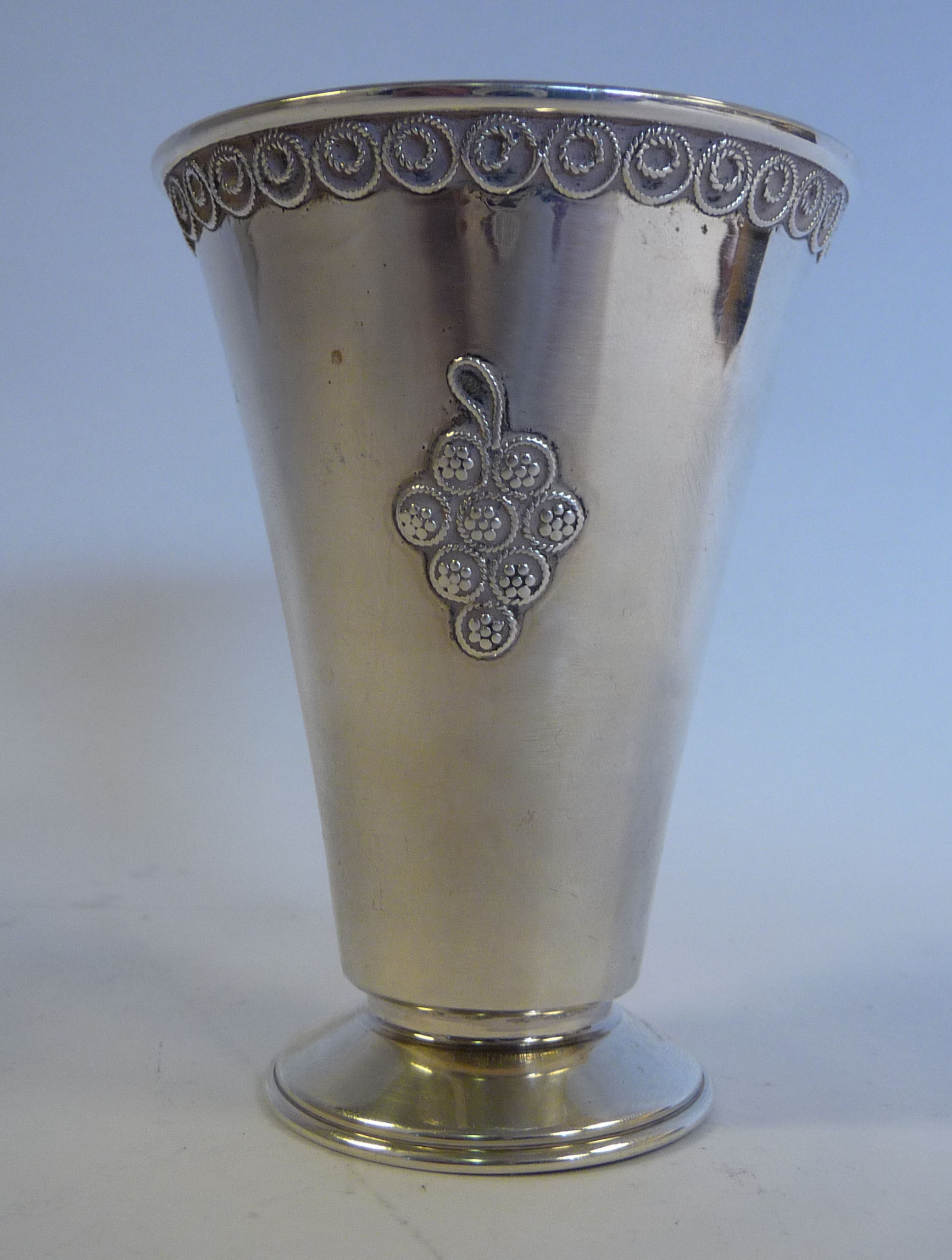 A foreign silver coloured metal beaker of tapered form, on a splayed footrim,