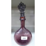 A 19thC semi-opaque blackcurrant coloured glass bottle of flattened flask design and a long ring