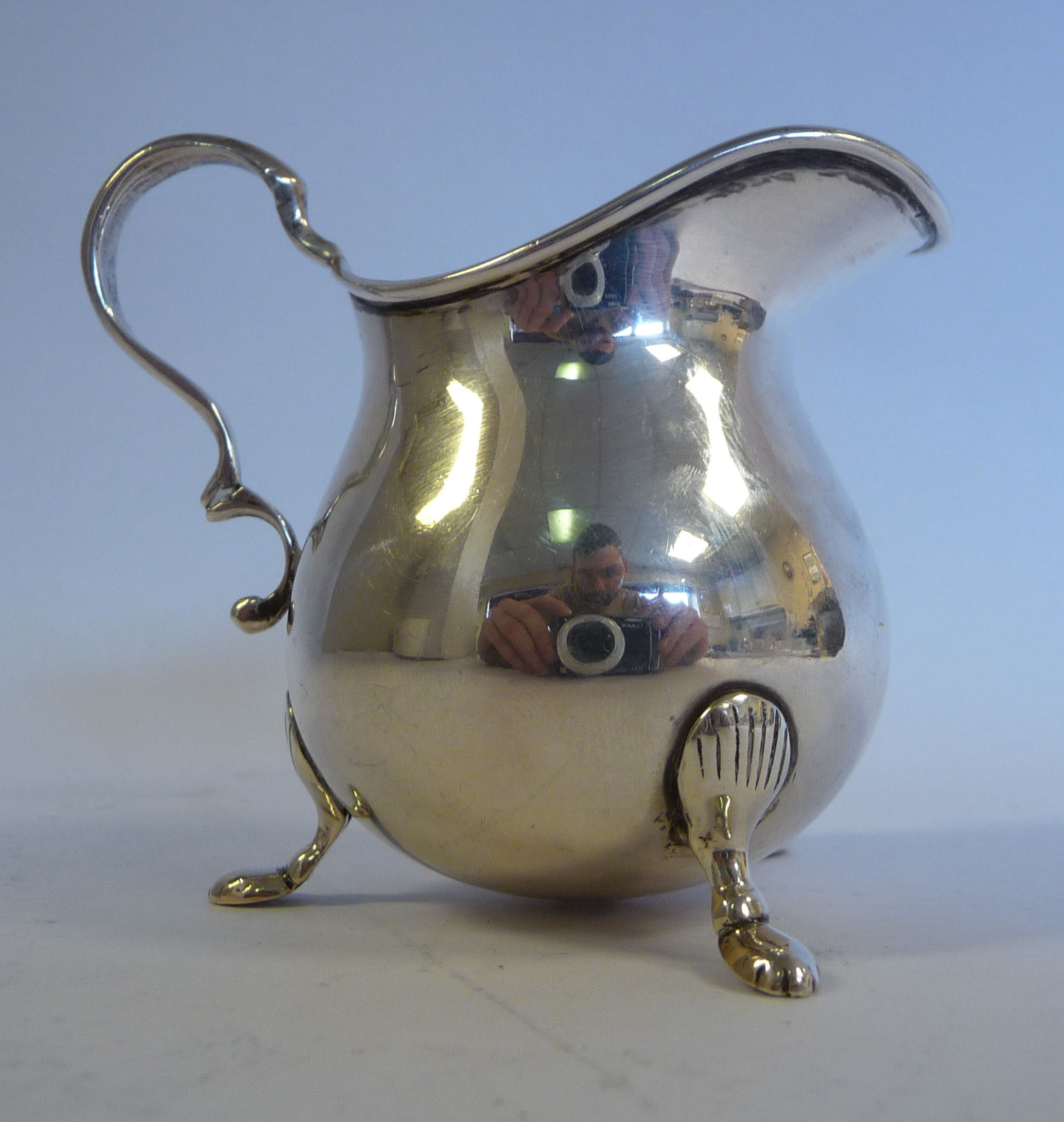 A Georgian style silver cream jug of waisted bulbous form with a flared,