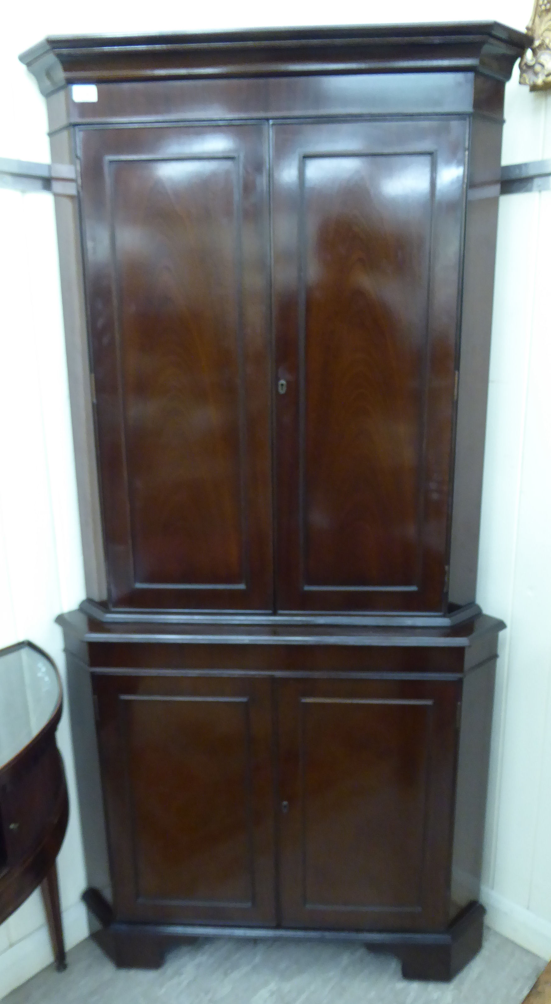 A modern Georgian style mahogany finished corner cupboard with canted sides,