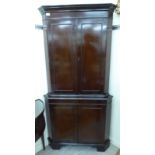 A modern Georgian style mahogany finished corner cupboard with canted sides,
