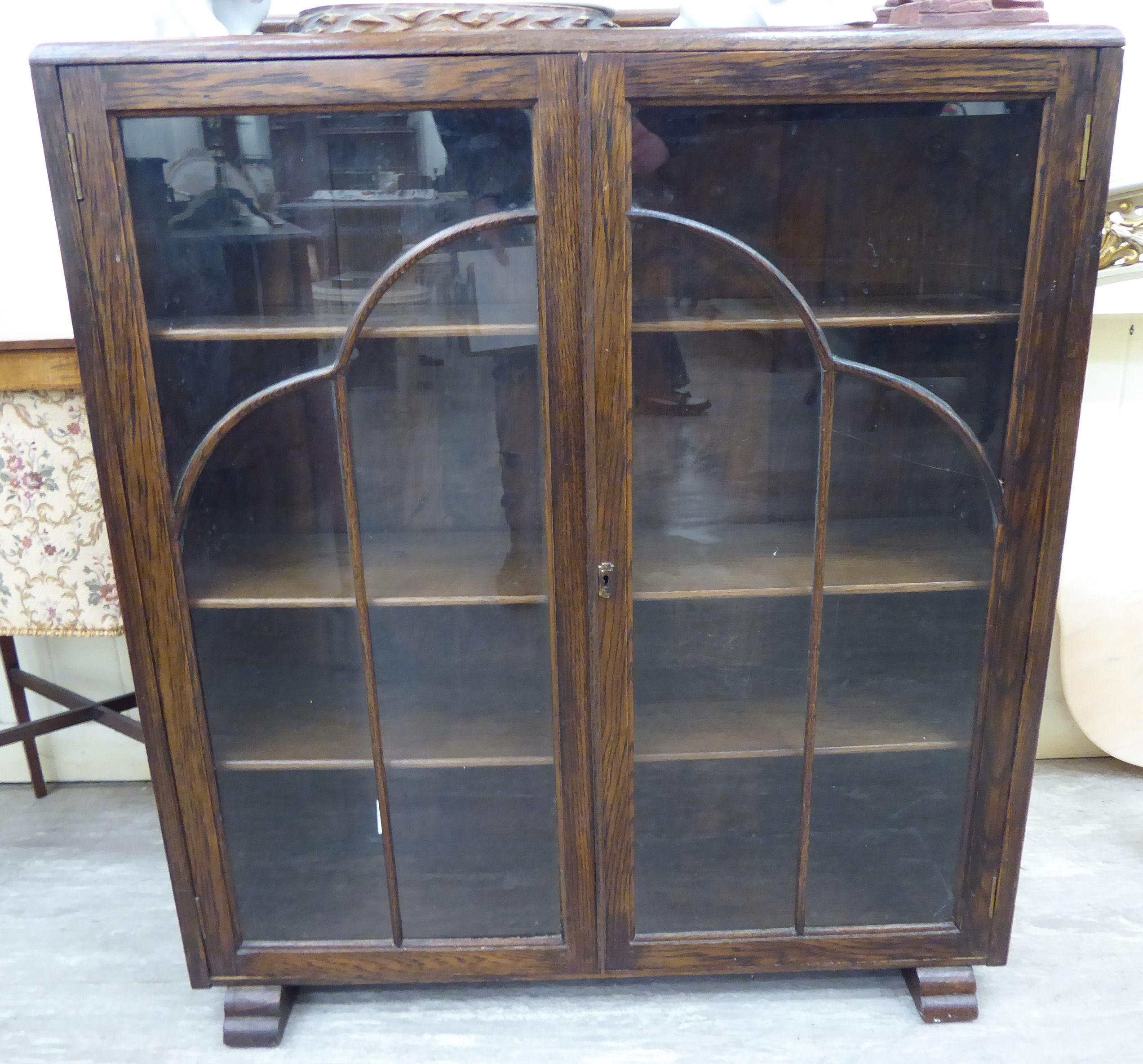 A 1930s oak display cabinet, enclosed by a pair of full-height, glazed panelled doors,