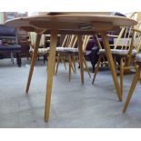 An Ercol light coloured elm and beech dining table, the oval top with a round edge and twin,