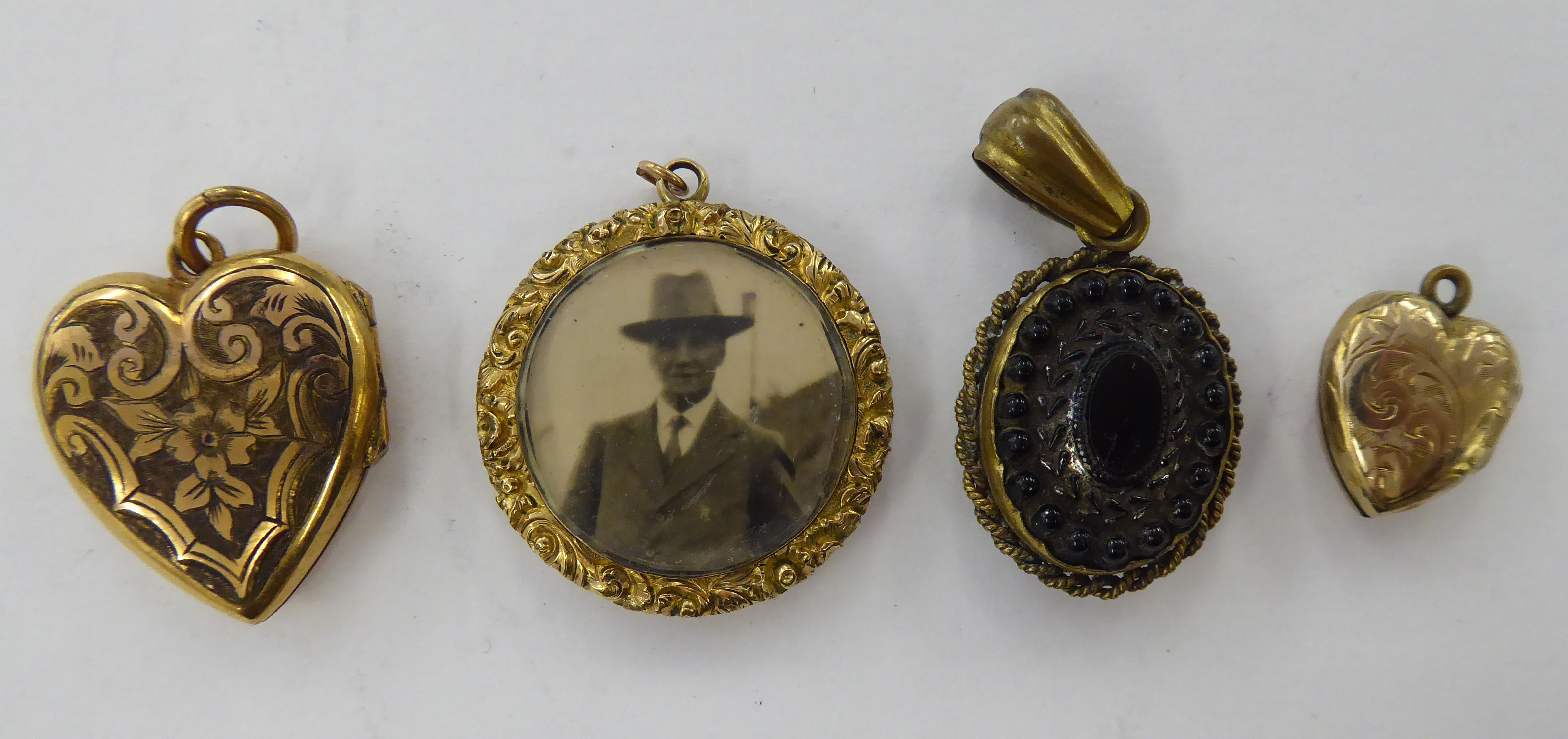 Four dissimilar 'antique' yellow metal lockets: to include one of heart design with floral engraved