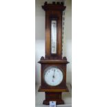 An Edwardian light oak cased aneroid barometer with carved, floral and castellated ornament,