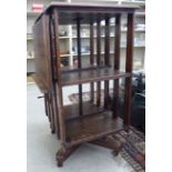 An Edwardian oak revolving bookcase, comprising two tiers with slatted sides and a folding lectern,
