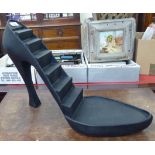 A retailer's display stand, fashioned as a lady's black, high heeled shoe,