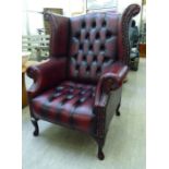 A modern Georgian style high wingback chair with scrolled arms,