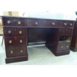 An early 20thC mahogany desk, the top set with a maroon fabric scriber, over three in-line drawers,
