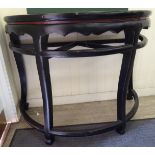 A 20thC Chinese black and iron red lacquered elm D-shaped console table with a wavy edged apron,