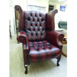 A modern Georgian style high wingback chair with scrolled arms,