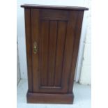 An Edwardian walnut pot cupboard with a low upstand, enclosed by a full-height panelled door,