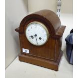 An early 20thC mahogany cased mantel clock with a round arch and beaded ornament,