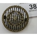 A white metal circular brooch, set with paste stones,