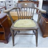 A 1920s unfinished, oak framed office chair with a scrolled bar crest and horseshoe shaped back,