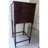 A Georgian mahogany pot cupboard, enclosed by a panelled door, raised on ring turned, spindled legs,