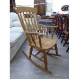 A modern pine framed rocking chair with a curved crest, lath back, swept open arms,