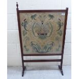 An early 20thC mahogany framed firescreen, set with a glazed, embroidered silk tapestry panel,