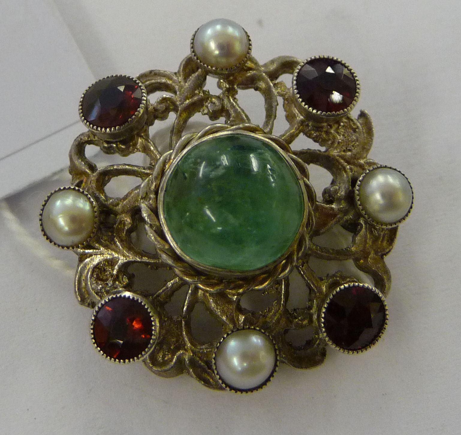 A white metal brooch, set with a green stone,