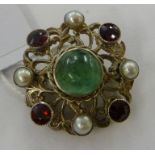 A white metal brooch, set with a green stone,