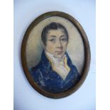 An early 19thC oval head and shoulders portrait miniature, a young man wearing a topcoat and cravat,