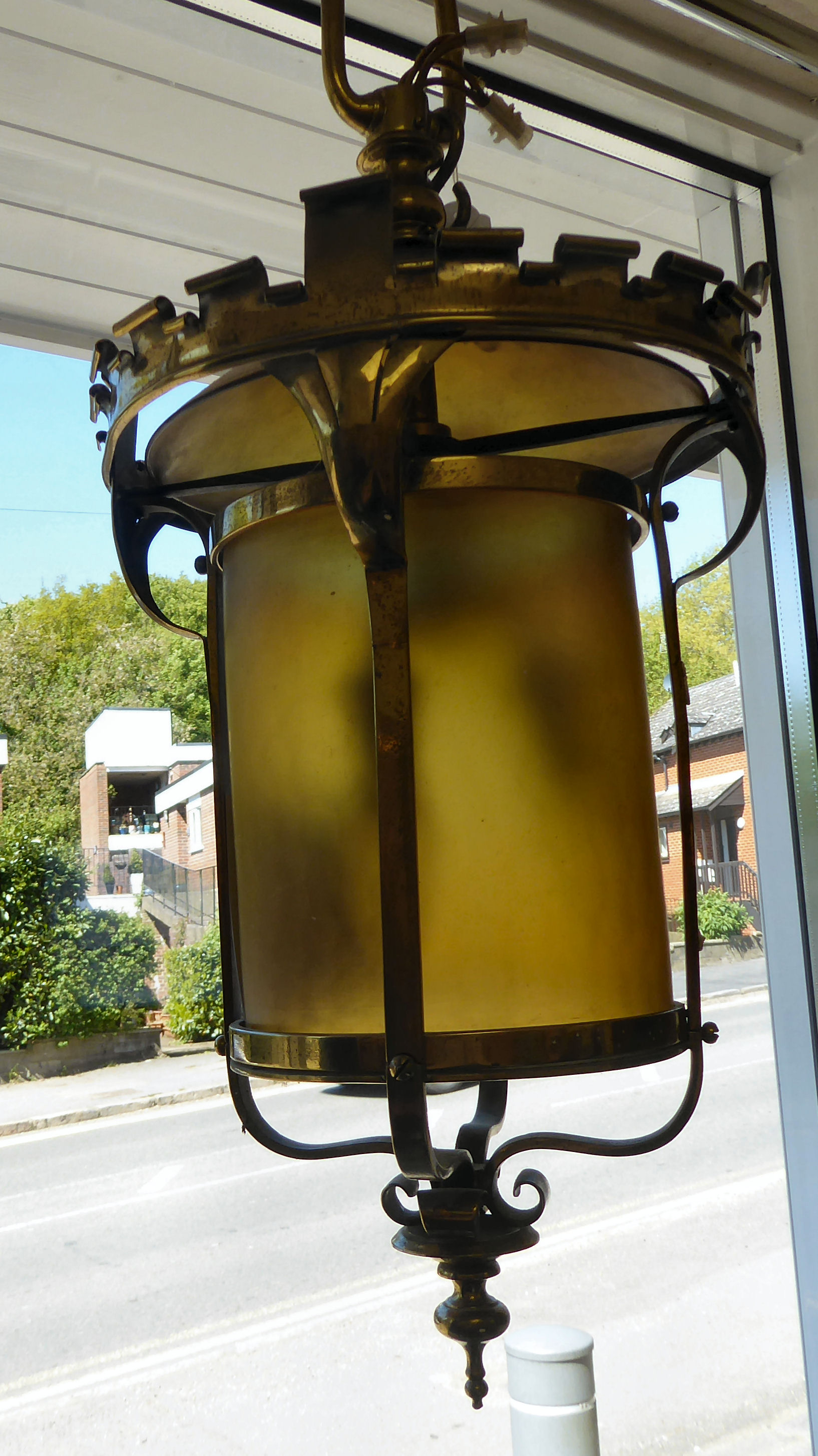 An early 20thC lacquered brass framed hanging lantern with a scrolled,