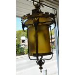 An early 20thC lacquered brass framed hanging lantern with a scrolled,