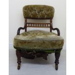 An early 20thC mahogany framed nursing chair with a low, curved crest,