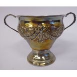A silver bowl of pear design with a flared rim and opposing beaded loop handles, embossed flora,