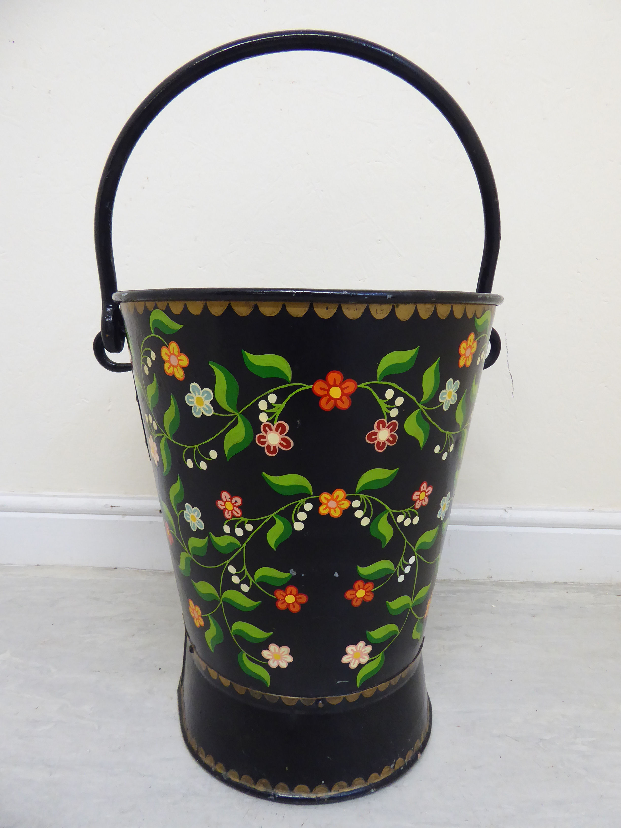 A late 19th/early 20thC Toleware bucket of tapered and waisted oval form with a rivetted fixed and