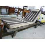 A modern teak framed poolside day-bed of slatted construction with an angled back,