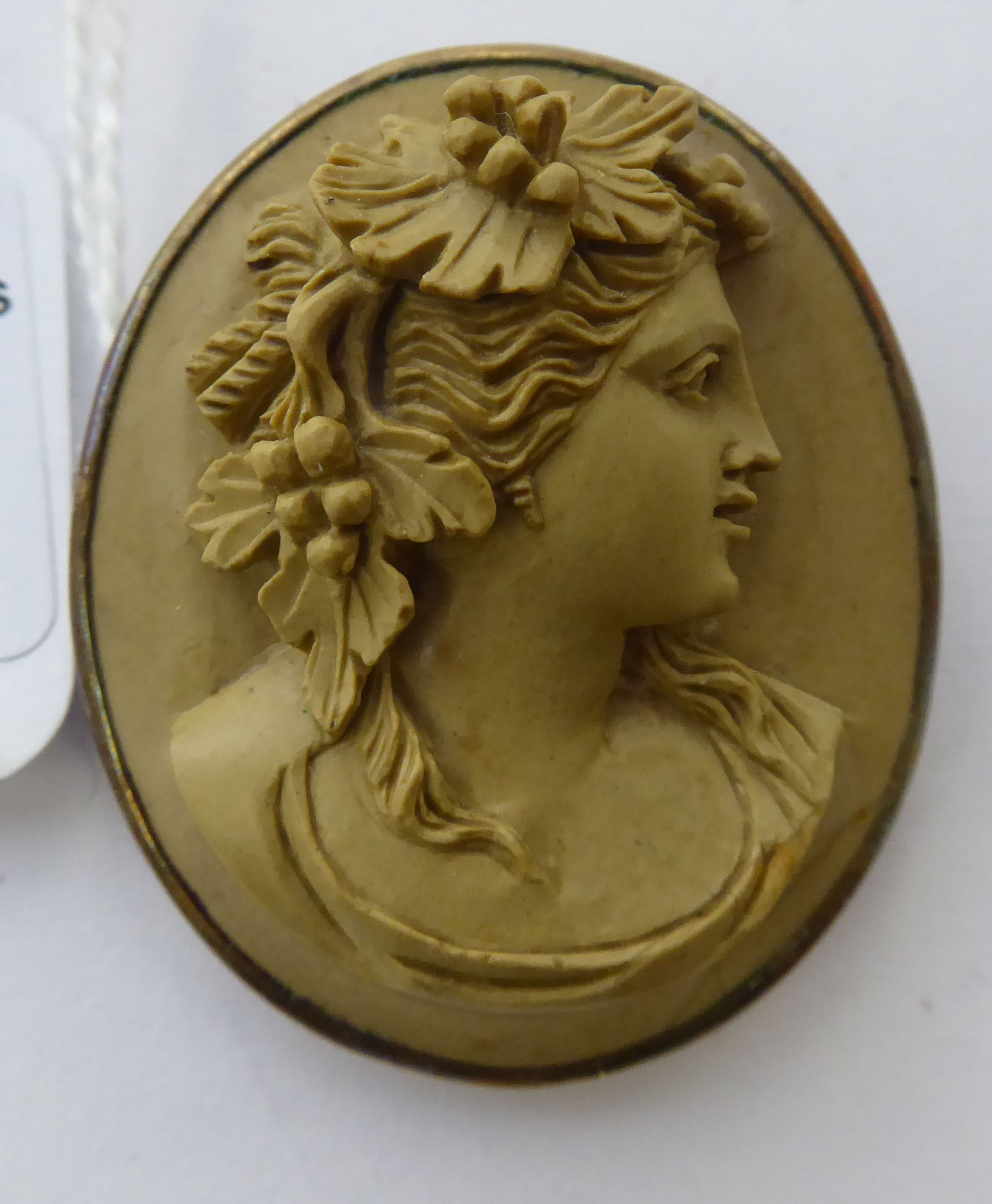 A late 19thC oval, yellow metal framed carved hardstone profile cameo portrait brooch,