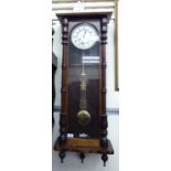 An early 20thC glazed mahogany cased Vienna wall clock with turned pilasters and drop finials;