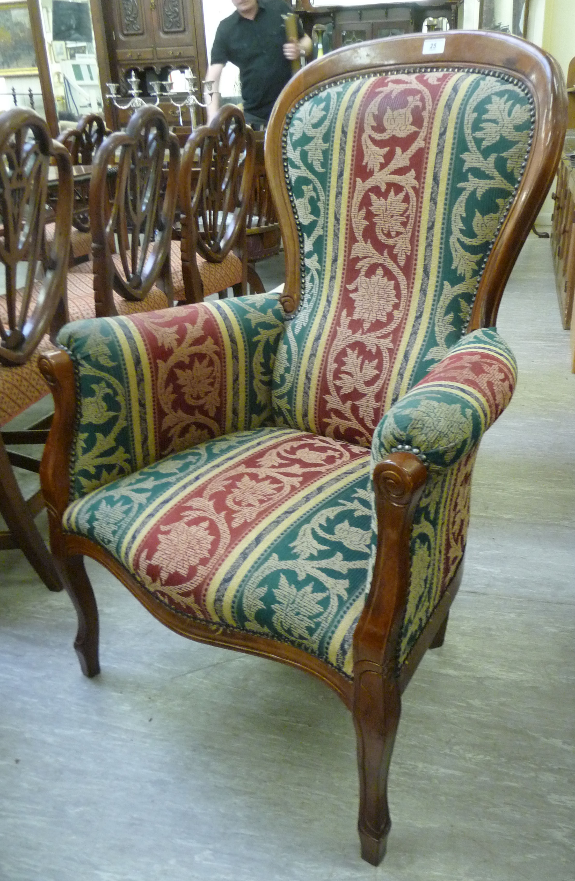 A Victorian style mahogany showwood framed spoonback chair with enclosed arms,