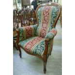 A Victorian style mahogany showwood framed spoonback chair with enclosed arms,