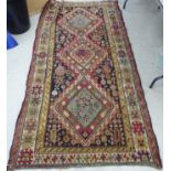 A Caucasian rug with three diamond shaped medallions and geometric motifs on a black and cream