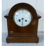 An early 20thC mahogany cased mantel clock with a round arch and beaded ornament,