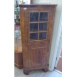 A 20thC walnut veneered corner cabinet with an astragal glazed door and a panelled door,