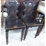 A pair of William IV stained mahogany hall chairs, each with a carved back,