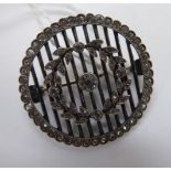 A white metal circular brooch, set with paste stones,